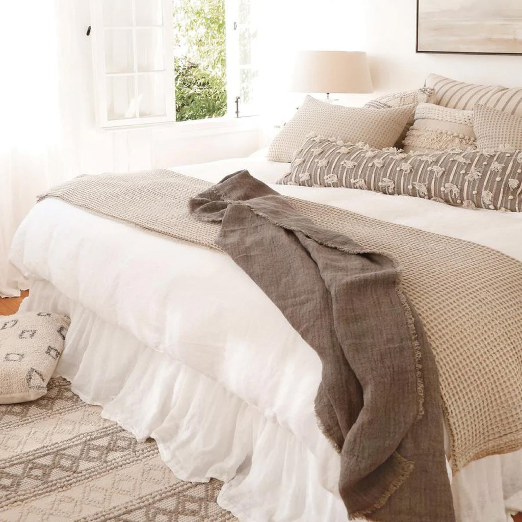 white bedroom with flowy bed skirt taupe pillows 