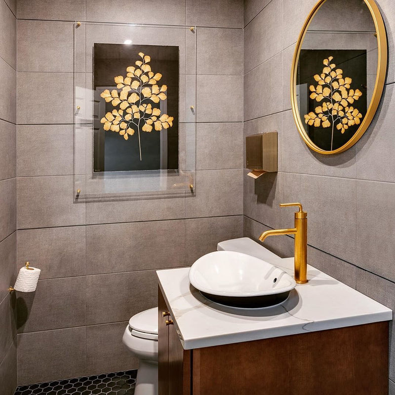 Modern bathroom with round mirror, gold faucet, vessel sink, and gray tile walls. The space is elevated by a stunning piece of framed Golden Owl Kozo Noire Photography Art from Barloga Studios, meticulously crafted on Japanese mulberry paper.