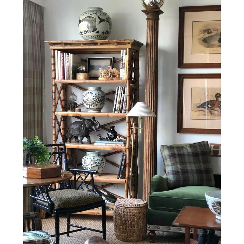 Cozy living room with a Tortoise Shell Bamboo English Bookcase by Kenian, green armchair, vases, and framed art.