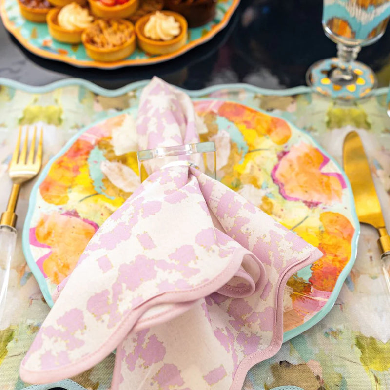 A vibrant tablescape featuring a floral plate, Marigold Melamine Pasta Bowls by Laura Park Designs, a pink napkin, and gold cutlery beautifully arranged on a patterned tablecloth.