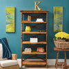 Kenian's Tortoise Shell Bamboo English Bookcase with decor and yellow flowers, flanked by green abstract paintings.