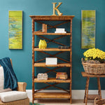 Kenian's Tortoise Shell Bamboo English Bookcase with decor and yellow flowers, flanked by green abstract paintings.