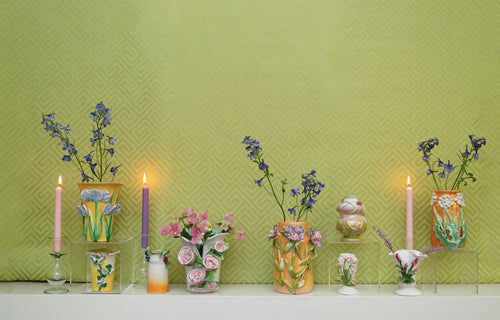 Handmade Mango with Lavender Flower Vase by Abigails and lit candles on a shelf against a textured green wall.