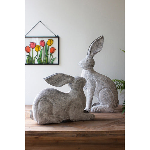 Kalalou's whimsical Rustic Metal Rabbits set on a wooden table, below a vibrant tulip picture.