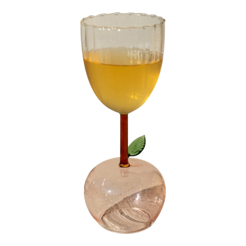 An Apple Base Wine Glass from Kalalou, with orange liquid and a leaf