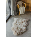 Room with a Natural Longwool Sheepskin Nappa Pelt Rug by Auskin and a wooden chair by the window, draped with a soft blanket.