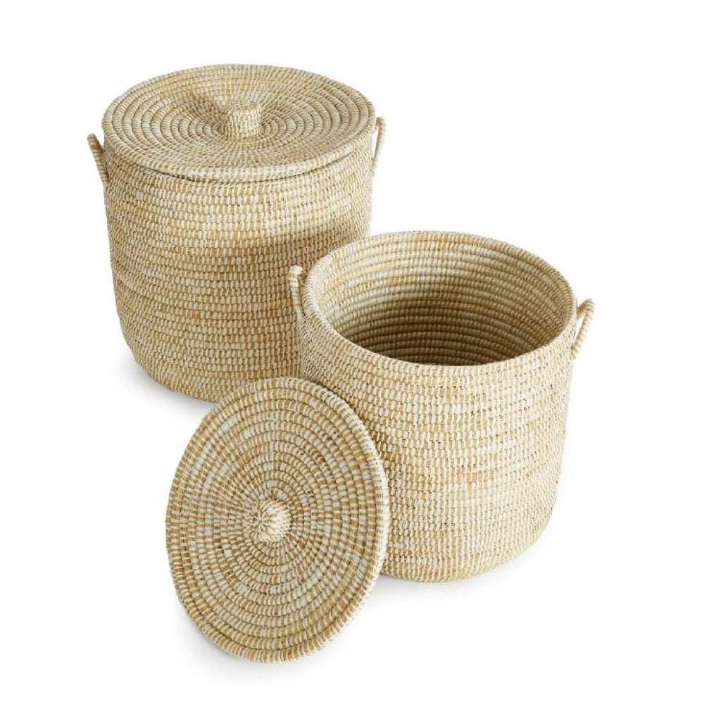 Two Rivergrass Hamper Baskets from Napa Home & Garden; one is closed with its lid, and the other is open, showcasing the hand-woven interior. These wicker baskets add a coastal vibe to any room.