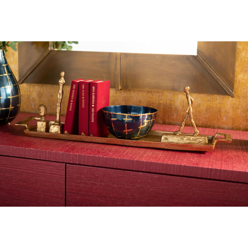 The Loom Small Bowl by Villa & House is artfully displayed on a red cabinet, accompanied by books and sculptures, highlighting hand-crafted metal elegance against the backdrop of a gold mirror.