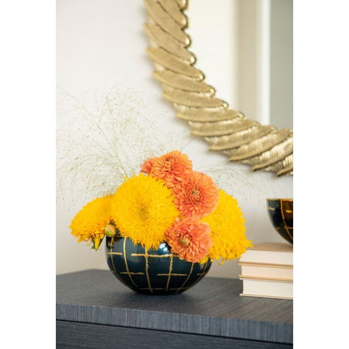 A Loom Medium Bowl by Villa & House sits elegantly on a table, its charm complemented by stacked books and a decorative mirror with a high shine finish, reflecting light beautifully.