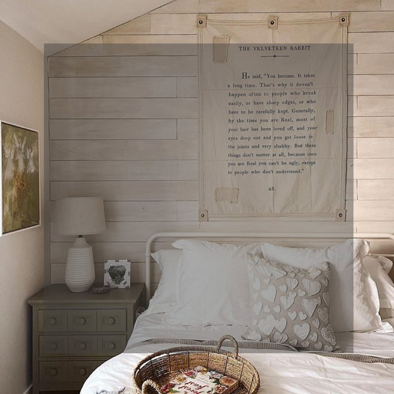 A cozy bedroom with a white bed, a heart-patterned pillow, a side table, and 