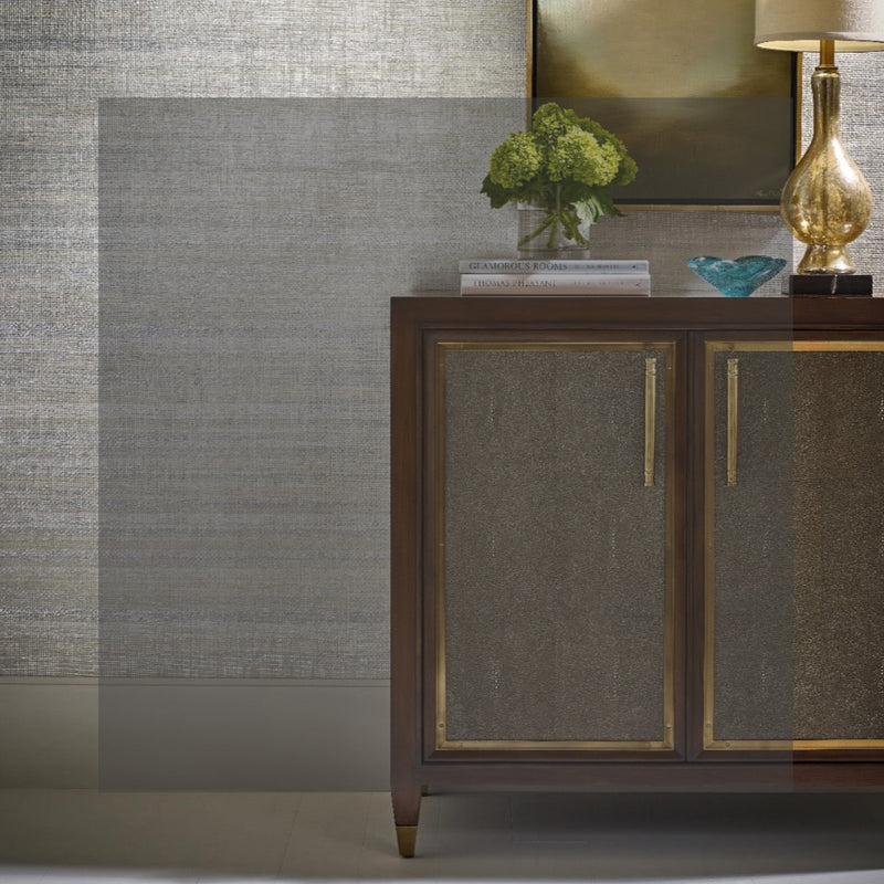 A wooden sideboard with vases, books, and a lamp on top in a modern living room setting.