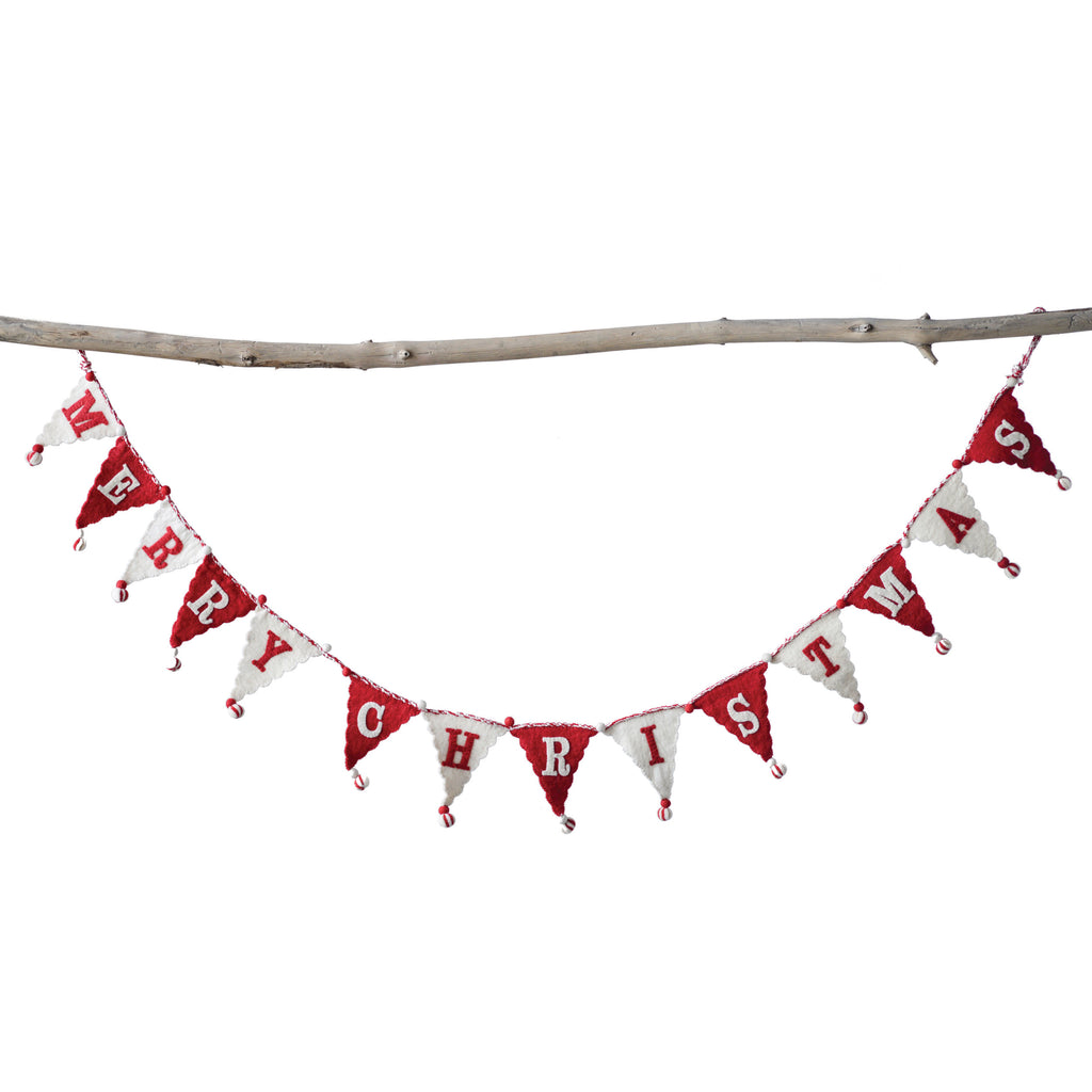 The Wool + Felt Merry Christmas Pennant Banner by BSEID, featuring red and white flags, drapes beautifully on a branch to enhance the holiday ambiance with festive charm.